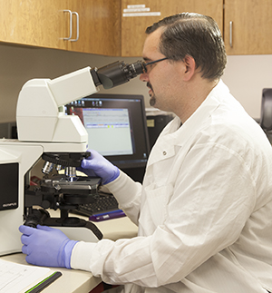 Lab technician looking through microscope.